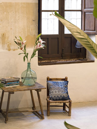 mesilla con silla frente a muro de piedra y ventana junto a planta